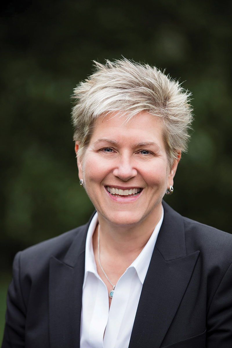 Tricia Benson wearing a black jacket and white shirt in a portrait.