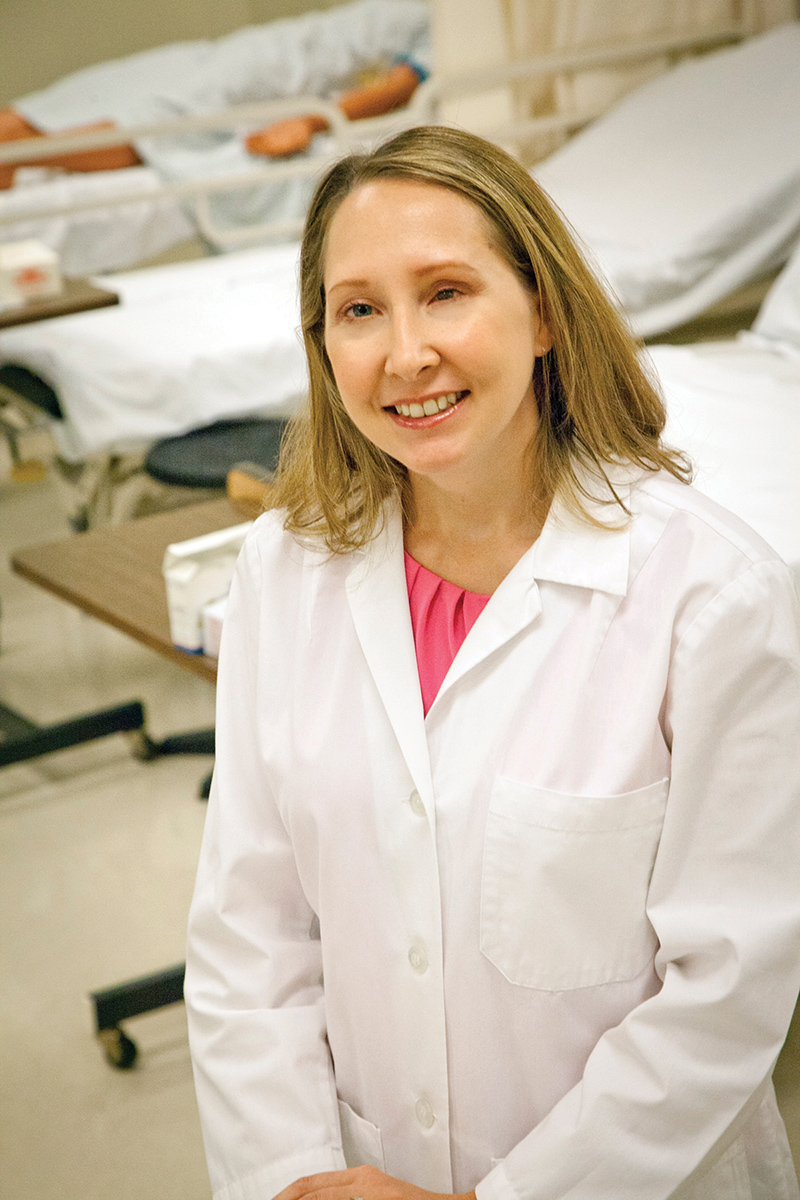 Melissa Owen wearing a white lab coat in a hospital setting.